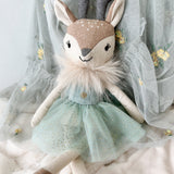 Stuffed deer toy with a green dress on a soft white background