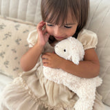 Child holding a white plush toy on a light-colored couch